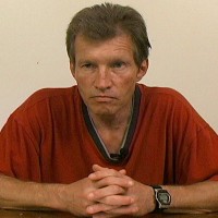 Andy Fine Unsmiling man with brown and gray hair wearing a red shirt